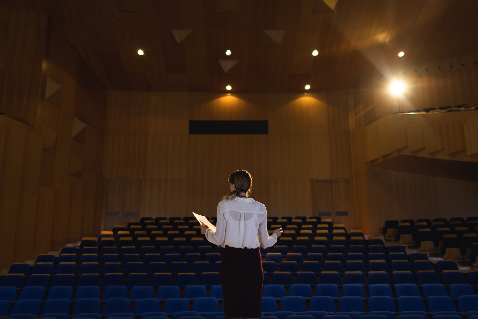 beautiful-businesswoman-practicing-and-learning-script-while-standing-in-the-auditorium (1)