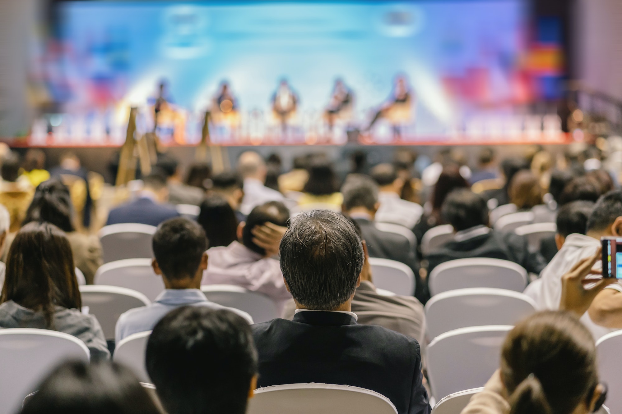 rear-view-of-audience-listening-speakers-on-the-stage-in-the-conference-hall-or-seminar-meeting